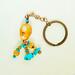 Handmade orange coral and turquoise beaded keychain with copper ring, shown on neutral background.